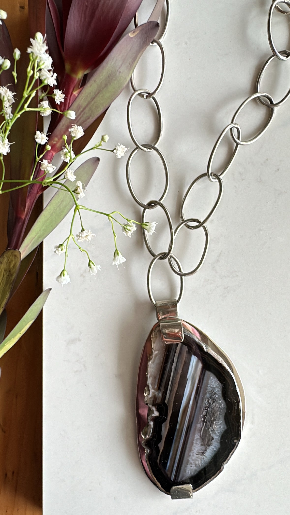 π§π₯ππ‘π¦π. πππ‘πππ₯ππ $ππππ Colgante de cadena con eslabones color plata y piedra natural en tonos negro y gris.